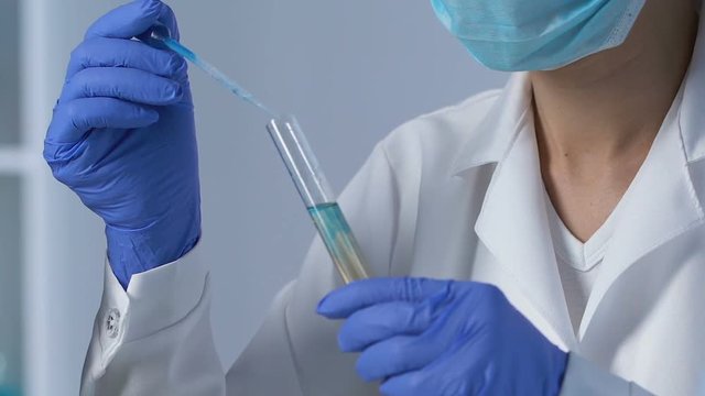 Lab assistant adding reactant to drinking water sample to determine sediments