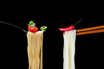 Hot spagetti on the fork with tomato and parsley and Asian noodles on chopsticks with red pepper.
