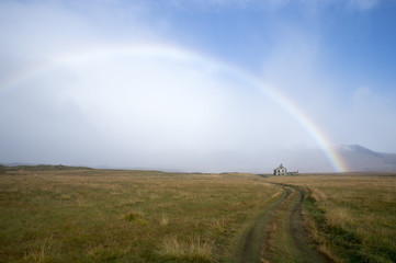 Full rainbow above road and white house