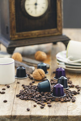 Italian espresso coffee capsules or coffee pods with espresso cups and coffee beans on a rustic wood background. Coffee accessories composition