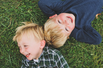 Two boys laughing and laying in the grass