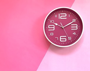 Closeup A deep pink wall clock set on pastel pink  background. Theme of Working business time .The concept of " The time is going on." Top view with Selective focus. Copy space.