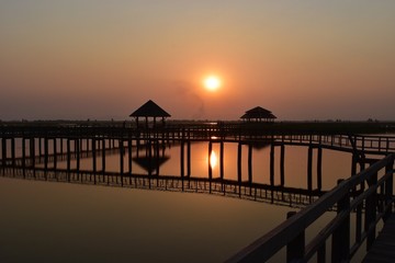 Khao Sam Roi Yot National Park ,Silhouette of Wooden bridge and pavilion, The path on the lagoon,Wetland,Sky turn orange at sunset ,Reflecting on water, Buang Bua, Thailand 
