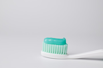 Green toothpaste on a toothbrush on white background