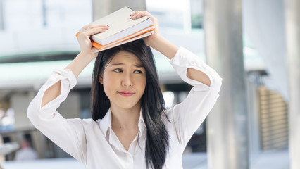 girl hold book up on the head with feeling thinking