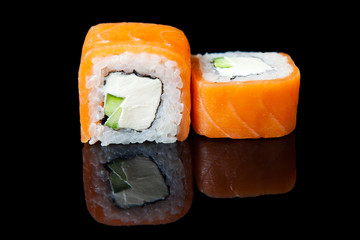 Traditional fresh japanese sushi rolls on a black background with reflection.