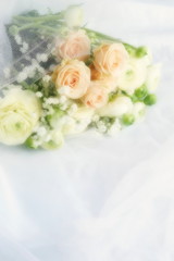 Blure effect, soft focus. Beautiful bridal bouquet from pale pink roses and white ranunculus flowers on white linen fabric background. copy space