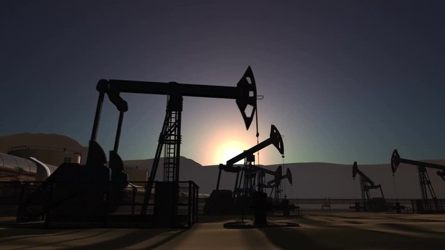 Sunrise over oil field with oil pump jacks and oil pipeline