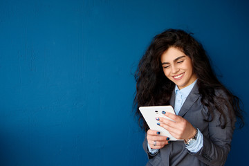 Fototapeta premium Girl with a tablet in hands on background a concrete wall. Online education students
