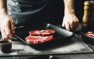 Foto op Canvas Male hands holding grill pan with raw beef steak © kucherav