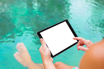 Man using tablet while sitting by the pool