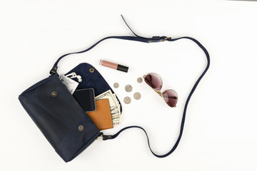 Close up of woman bag open out with smartphone, passport, earphone, condom, dollars on white, top view, flat lay