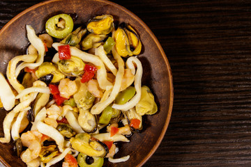 Seafood salad with shrimp, squid and mussels on wooden table
