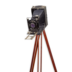 Old camera with bellows on wooden tripod on white background