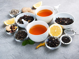 Cups of tea with aromatic dry tea in bowls