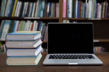 Laptop, Book stack in the library room and blurred bookshelf for business and education background, Back to school concept