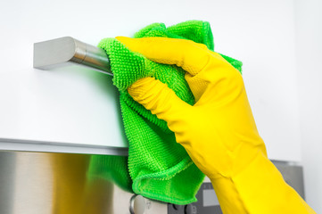 Hand in glove with green rag is cleaning stainless steel handles