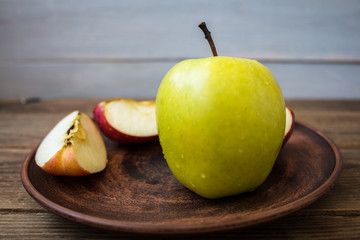 green apple on a plate on wooden background