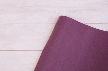 Yoga accessories, open  exercise mat on white wooden background with copy space. Concept for ashtanga yoga practice.