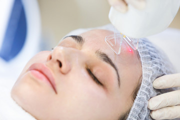 Obraz na płótnie Canvas close up beauty procedure. Professional beautician making facial peeling in a forehead. Laser face peeling.