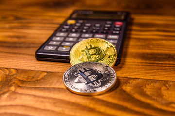 Bitcoins and scientific calculator on a wooden table