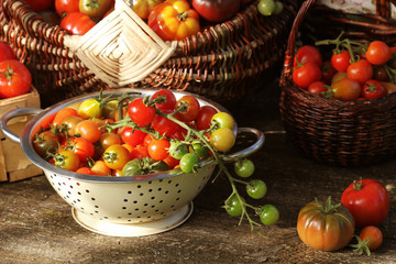 Fototapeta na wymiar Heirloom variety tomatoes in baskets on rustic table. Colorful tomato - red,yellow , orange. Harvest vegetable cooking conception