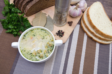 Mushroom soup with croutons in a white dish is on a wooden table.