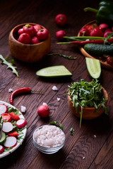 Creative fresh vegetable salad with ruccola, cucumber, tomatoes and raddish on white plate, selective focus