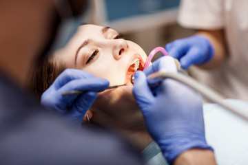 Male dentist treating teeth to young woman patient in clinic. - 200849086