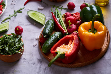 Still life of wooden plate with vegetables on white textured background, close-up, selective focus