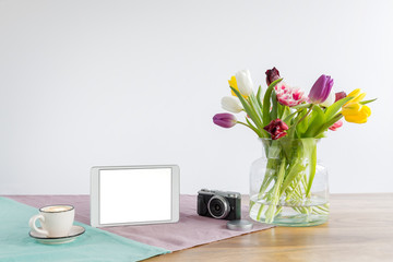 Tablet screen with copy space and flowers on wooden desk with white background