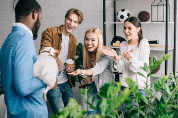 smiling business coworkers touching dog on hands of african american businessman