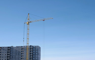 Construction of a multi-storey building. Crane on sky background.