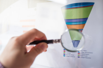Colourful sales funnel chart under a magnifier lens for marketing data analysis