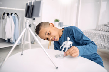 New model. Glad afro american boy blogger recording video while scrutinizing toy