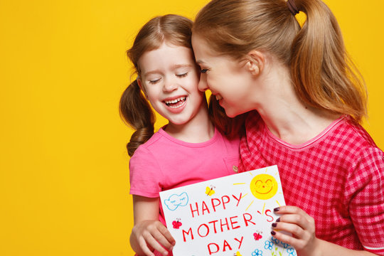 concept of mother's day. mom and child girl with postcard on colored background