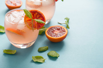 Blood orange cocktail with slices of orange on turquoise background