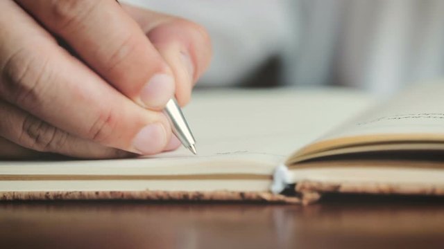 close up hands writing on the diary book in living room