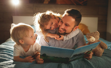 evening family reading. father reads children . book before going to bed .