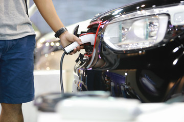 Obraz premium man with power supply for electric car charging. Electric car charging station