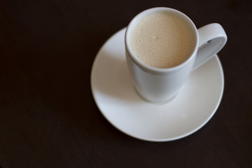 A cup of cappuccino coffee on a brown table, copy space
