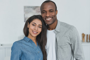 smiling african american girlfriend and boyfriend looking at camera at home