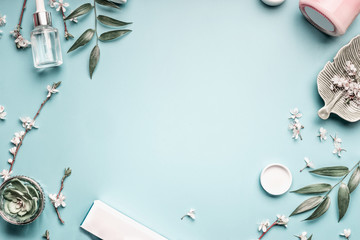 Facial cosmetic products, leaves and cherry blossom on blue table - obrazy, fototapety, plakaty
