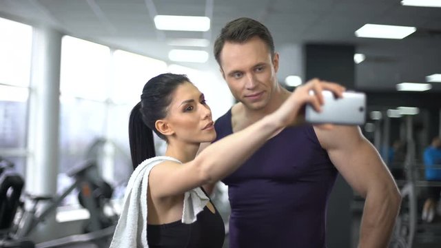 Young man and woman taking selfie in gym, modern technology, social networking