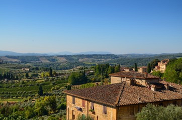 Fototapeta na wymiar San Gimignano, Italy, Tuscany region. August 14 2016. Landscape seen from the top of San Gimignano towards the valley. Green hills alternate with vineyards and fields cultivated in the countryside.