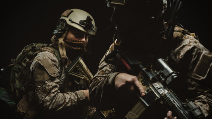 soldiers or private military contractors holding rifle. Image on a black background. war, army,...