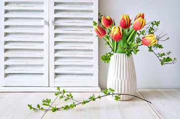 Springtime greeting card design with bunch of red tulips and Spring leaves on light wood