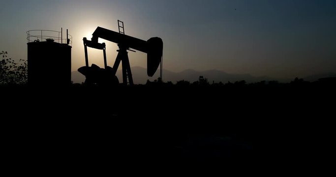Industrial oil pump jack pumping crude oil for fossil fuel energy with drilling rig in oil field.