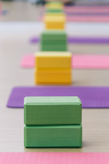 Colourful yoga blocks and mats place on wooden texture floor. Ready for yoga class.