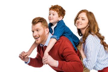 happy parents with cute little son smiling and looking away isolated on white